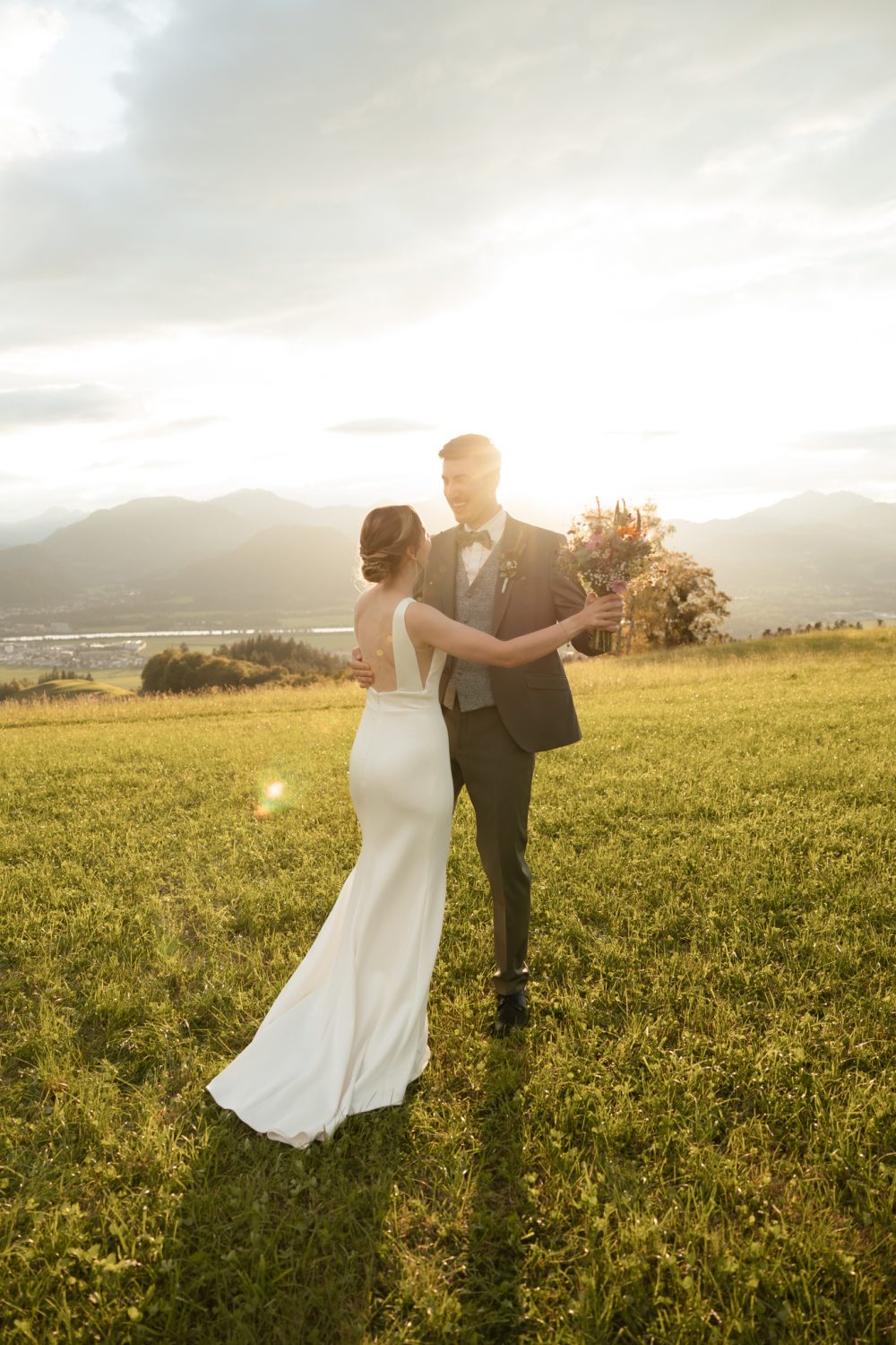 Brautpaar geht im Gegenlicht über eine Wiese (Beispielbild aus einer Sommerhochzeit)