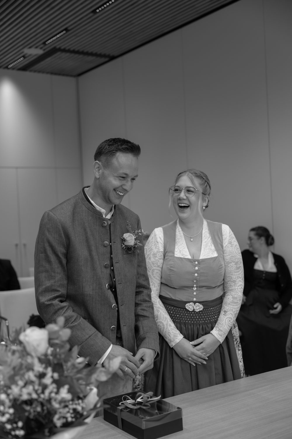 Bräutigam und lachende Braut in Tracht im Trauzimmer (Schwarz-Weiß-Aufnahme)