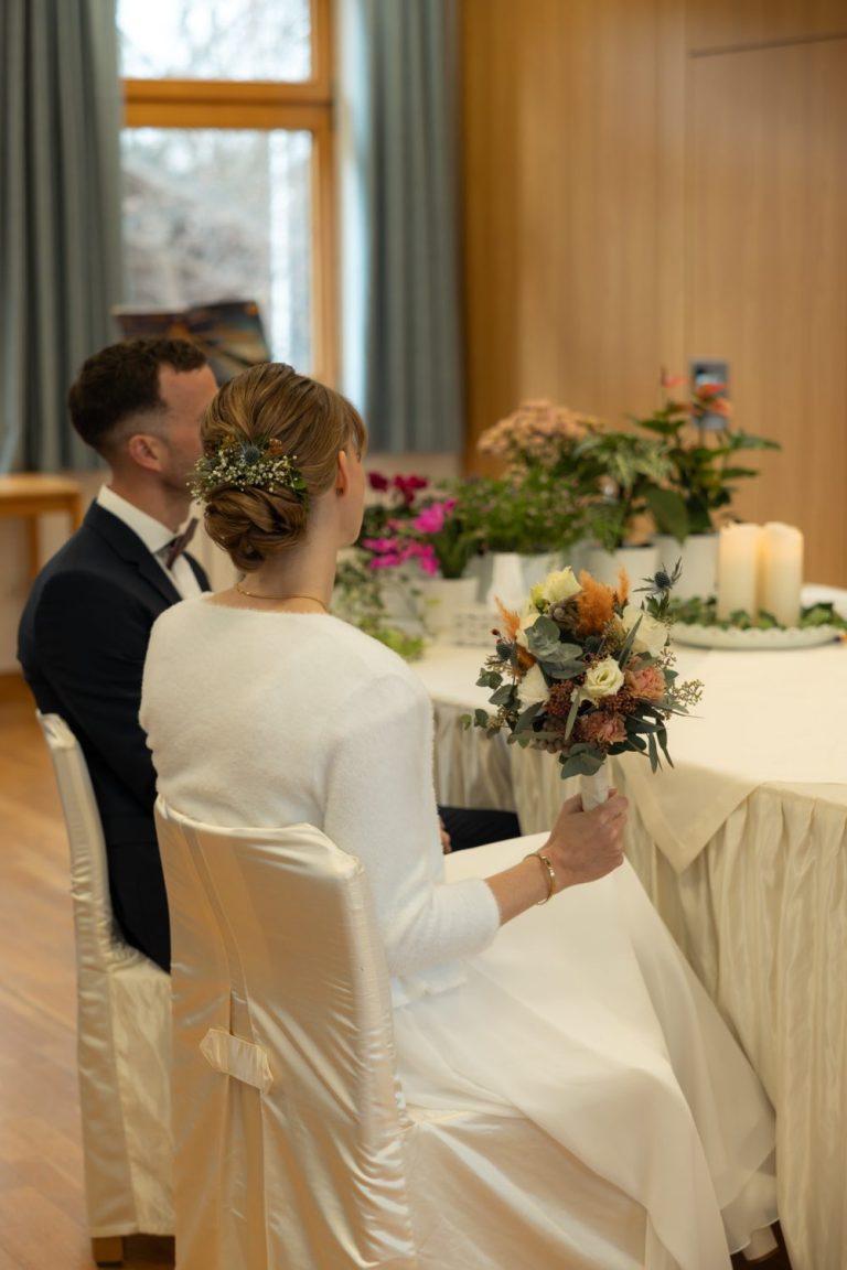 Brautpaar am festlich mit Blumen und Kerzen geschmückten Tisch